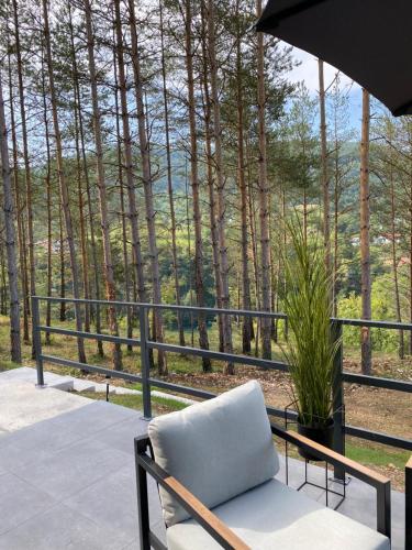 a chair on a porch with a view of trees at La Casa Cottage in Jajce