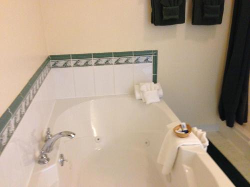 a bathroom with a tub with a sink and towels at The Falls Motel in Watkins Glen