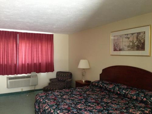 um quarto de hotel com uma cama e uma cadeira em The Falls Motel em Watkins Glen