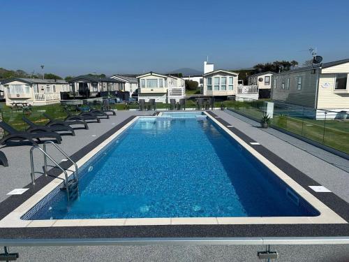 a swimming pool in a yard with chairs and houses at Ty hedd static caravan in Caernarfon