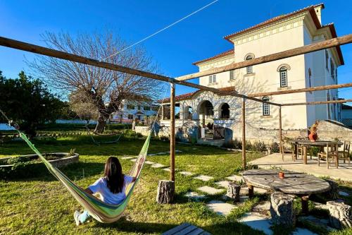 a woman sitting in a hammock in front of a building at Train Spot Guesthouse in Marvão