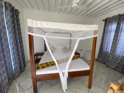 a bed with a canopy in a room at Karibu House Paje in Paje