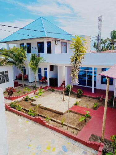 a large white house with a blue roof at Karibu House Paje in Paje