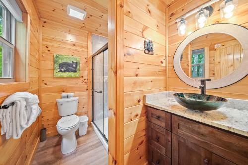 a log cabin bathroom with a sink and a toilet at Poolin Around by American Patriot Getaways in Glade