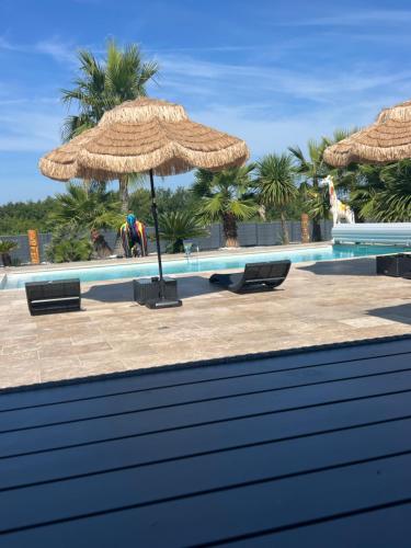 a swimming pool with a straw umbrella and benches at Luxury home private duras in Duras