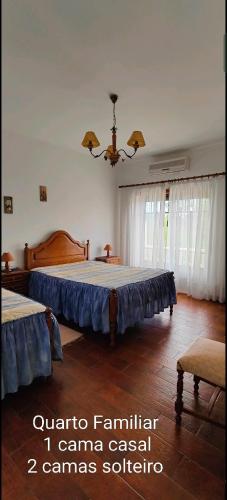 a bedroom with two beds and a chandelier at Alojamento Local Céu-Azul in Porto de Mós