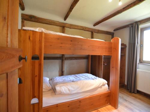 a bunk bed in a wooden room with a bed in it at Chalet Retreat with Sauna in Robertville