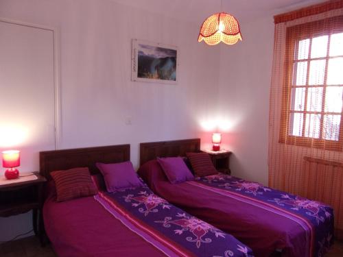 two beds in a room with purple sheets at Location Laroque Cévennes in Laroque