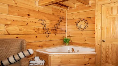 a bathroom with a tub in a wooden wall at Smoky Mountain Escape by American Patriot Getaways in Henderson Springs