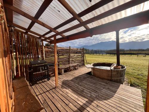 a wooden deck with a hot tub and a grill at Patagonia Puelo Lodge in Cochamó
