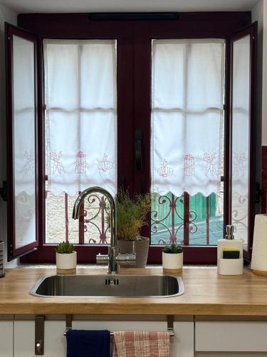 a kitchen with a sink and two windows at Casas do Abô Fredo in Sendim