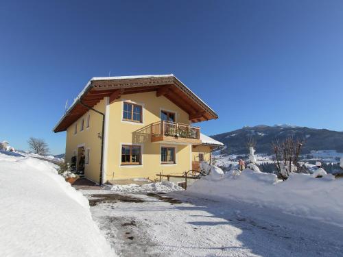 a yellow house with a balcony in the snow at Holiday Home in Taxenbach with Hohe Tauern Views in Taxenbach