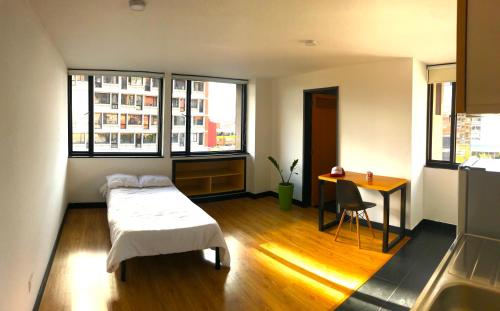 a bedroom with a bed and a table and windows at Habitaciones junto a Clinica Marly in Bogotá