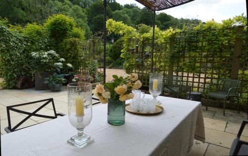 a table with two candles and a vase with flowers at Chandlers, fabulous great hall in the heart of Castle combe in Castle Combe