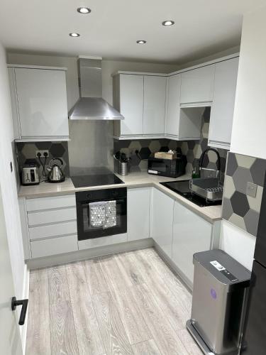 a kitchen with white cabinets and a stove top oven at Stylish City Retreat with Views & Court Yard in Leeds