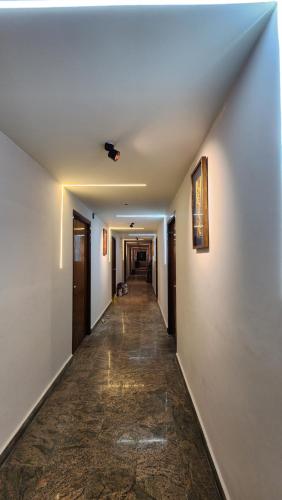 a long hallway with white walls and a long hallway with a long hallway at Hotel Maitreya Inn near CMC Hospital, VIT, Sripuram Temple,Naruvi Hospital in Vellore