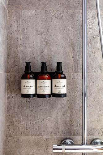 a group of four bottles on a shelf in a shower at NH Collection Andorra Palomé in La Massana