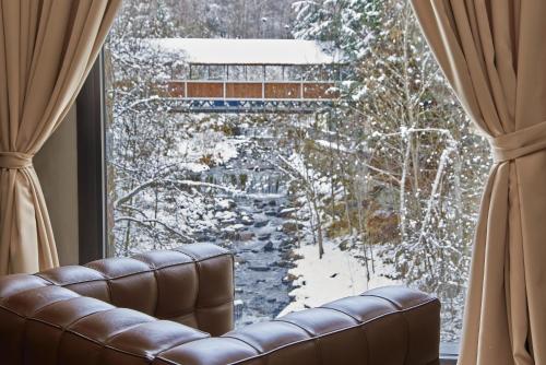 a couch in front of a window with a winter view at NH Collection Andorra Palomé in La Massana