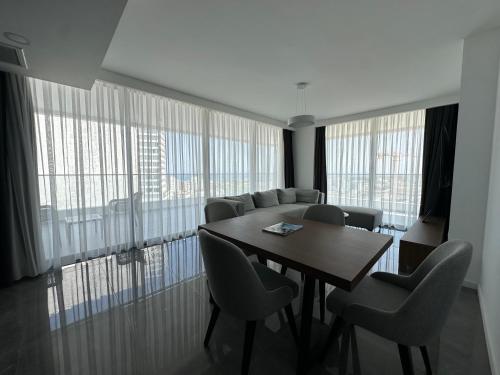 a dining room with a table and chairs and windows at Grand Sapphire Luxury Residence By MyGuest Cyprus in Iskele