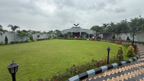 a large green yard with a building in the background at Niayra Farms by StayGram in Dharmpura