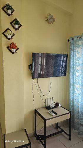 a room with a table and a tv on the wall at Shraddha hospitality in Calangute