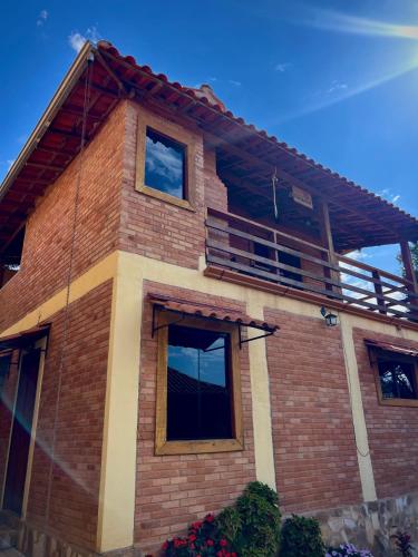 une maison en briques avec un balcon sur le toit dans l'établissement Casa Girassol, à Conceição da Ibitipoca