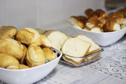three bowls of bread and buns on a table at Pousada Santa Rosa in Aparecida