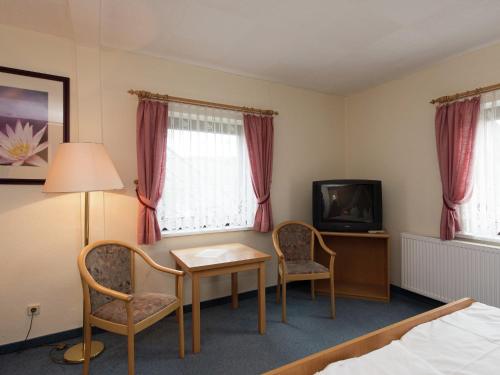 a hotel room with a table and chairs and a tv at Majestic Stay in Deutschneudorf in Deutschneudorf