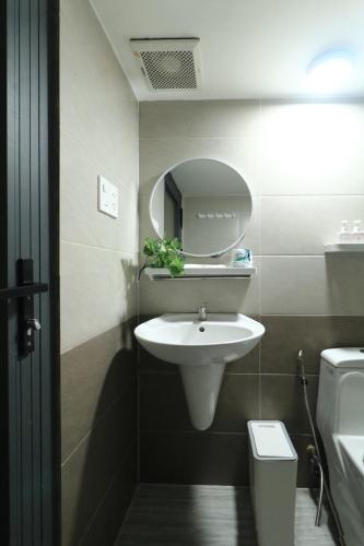 a bathroom with a sink and a mirror and a toilet at Nguyen's Home Saigon Airport in Ho Chi Minh City