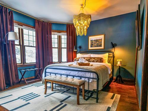 a bedroom with a bed with blue walls and a chandelier at Estello Suites & Spa in Lac-Mégantic