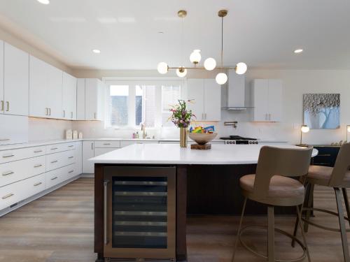 a kitchen with white cabinets and a island with chairs at Namaste on the Bay in Stevensville