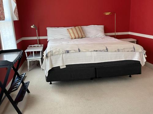 a bedroom with a large bed with red walls at Ferry View in Oxford