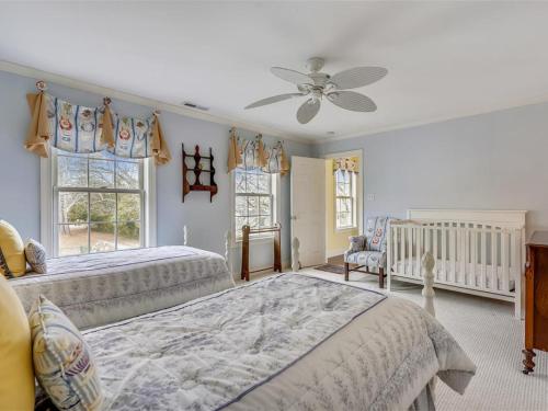 a bedroom with two beds and a crib and windows at Ferry View in Oxford