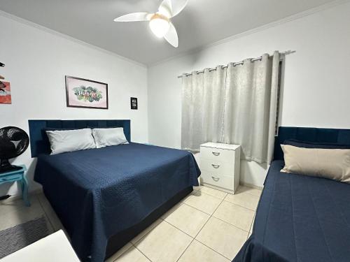 a bedroom with two beds and a ceiling fan at Apto 1 dorm no Canto do Forte - Próximo a Praia! in Praia Grande