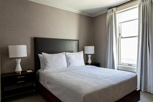 a bedroom with a bed with two lamps and a window at Hotel Richemont in Charleston