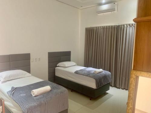 a hotel room with two beds and a window at Casa de alto padrão, 2 minutos do shopping in Tangara da Serra