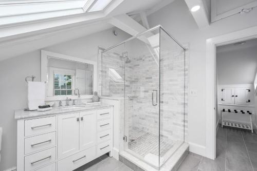a white bathroom with a shower and a sink at 530 Route 28 Harwich Port Cape Cod - - The Pineapple House in Harwich Port