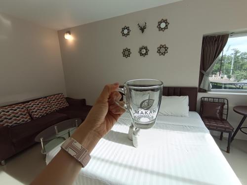 a person holding a glass in front of a bed at Makan Resort in Kanchanaburi