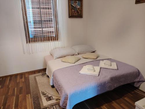 a bedroom with a bed with two towels on it at Apartman NINA in Ličko Petrovo Selo