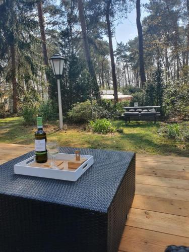 a bottle of wine and a tray of wine glasses on a table at Sfeervolle woodlodge op 5 sterren vakantiepark in Raalte