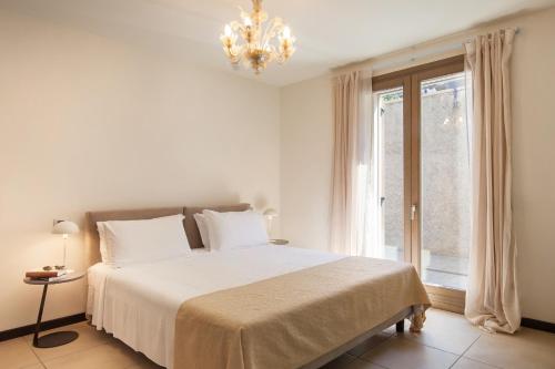 een slaapkamer met een bed met een kroonluchter en een raam bij Apartment Righini in Torri del Benaco