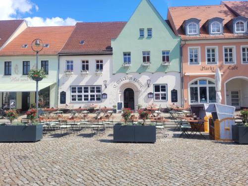 a group of buildings with tables and chairs in a courtyard at Kutscherhaus mit 2 Schlafzimmer im Zentrum von Senftenberg in Senftenberg