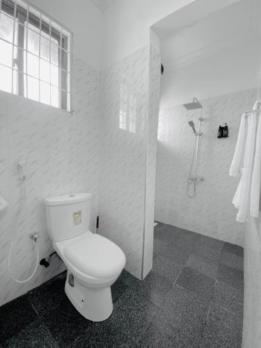 a white bathroom with a toilet and a shower at Karibu House Paje in Paje
