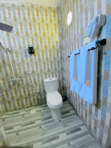a bathroom with a toilet and a shower with blue towels at Karibu House Paje in Paje