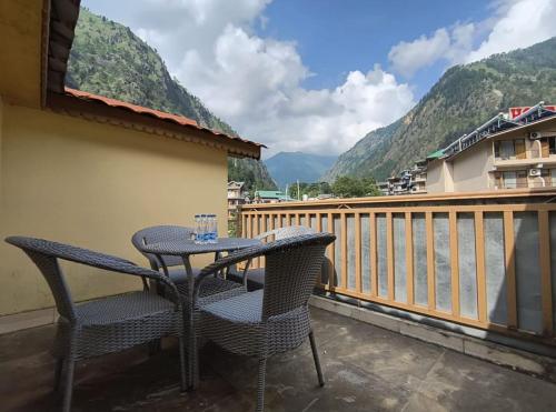 a table and chairs on a balcony with mountains at Hotel Purnima Kasol in Kasol