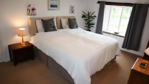 une chambre avec un grand lit blanc avec une fenêtre dans l'établissement The Old Farmhouse, Yealand Redmayne, near Carnforth, à Beetham
