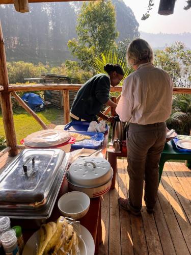 a couple of people standing around a table with food at Antique cottages in Kabale