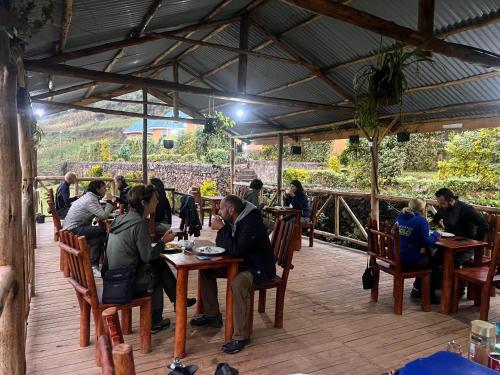 a group of people sitting at tables in a restaurant at Antique cottages in Kabale