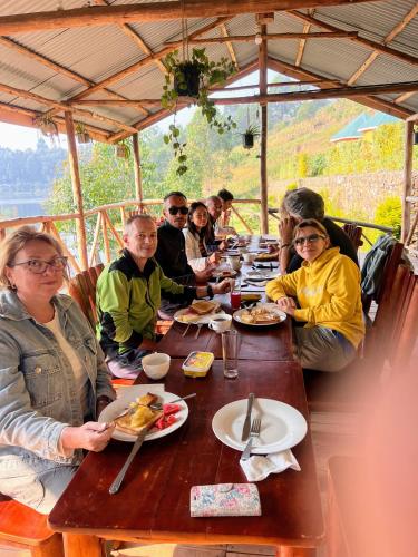 a group of people sitting at a table eating food at Antique cottages in Kabale