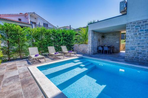 una piscina con 2 sillas junto a una casa en Apartment Siora, en Njivice